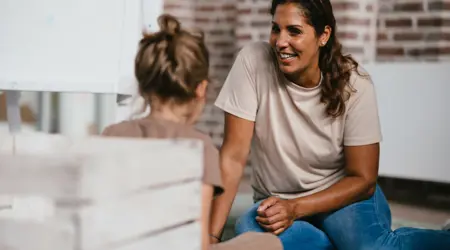 Pedagogisch Medewerker lacht naar kind op kinderopvang