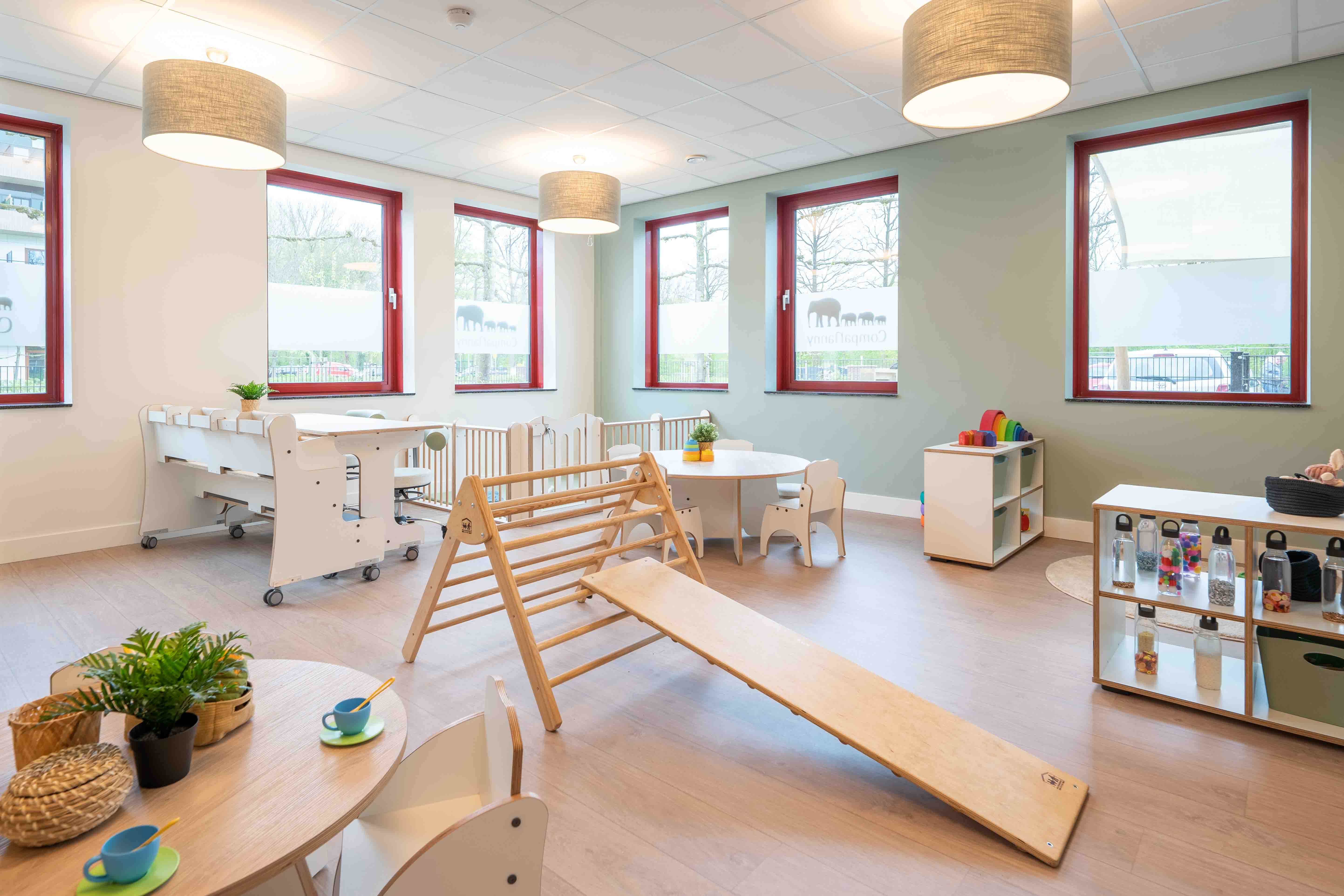babygroep inrichting met houten meubels grondbox en klimdriehoek